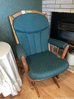 Full view of the wooden frame glider chair with green cushioned upholstery including seat, backrest, and armrests.