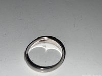 Close-up photo of the 10kt white gold ring showing the inner hallmark marking '10KT'. The ring has a smooth, polished finish and a plain band design.