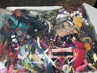 Image of sealed clear bag filled with assorted colorful jewelry including beads, wristwatches, and bracelets.