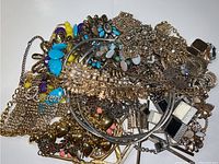 Photo showing a pile of assorted gold and silver tone necklaces with various crystals, CZ, gems, and mineral beads against a white background.