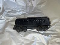 Side view of black Lionel Lines coal car showing 'LIONEL LINES' label and metal wheels on two bogies