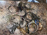 Various bracelets including silver, gold-tone, leather, and charms laid out on a surface.