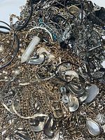 Close-up photo showing gold and silver necklaces and bracelets with various pendants and decorative elements mixed together.