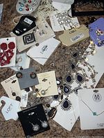 Mixed assortment of earrings and necklaces from brands including Kim Rogers, Loft, Cato, Bella Beads, and others, showing individual pairs and tags.