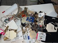 Pile of mixed new fashion jewelry with retail tags including necklaces and earrings from multiple brands