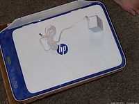 Top view of the HP device showing white and blue color with power adapter coiled on top