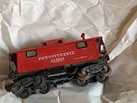 Side view of red Lionel Pennsylvania caboose with model number 472618, showing decals and wheels.