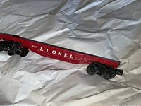 Side view of Lionel red cargo flat car showing number 6816 and 'LIONEL' lettering.
