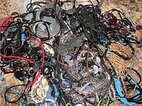 Photo showing the tangled assortment of silver and gold-tone pendants, black and red cords, seed bead necklaces and some translucent beads.