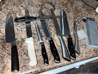 Entire set of knives and sharpening stones laid out on countertop, showing variety of knives and included honing steel