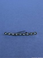 Close-up photo showing the full length of the vintage rhinestone pin with nine clear round rhinestones in a row on a metal backing.
