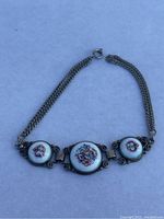 Full view of vintage silver chain bracelet with three porcelain floral medallions and spring ring clasp