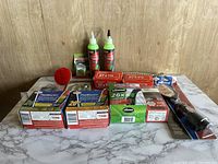 Wide shot of bike repair materials including boxes of tire patches, tire sealant, locks, chains, tire levers, and repair liquids on marble surface with wood background.