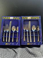 Two unopened Farberware 20-piece silverware sets shown in blue boxes with visible forks, knives, tablespoons, and teaspoons.