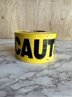 Front view of the yellow caution tape roll showing the letters 'CAUT' with some minor surface creasing.