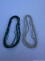 Two seed bead necklaces shown on blue background: one dark green single strand and one multi-strand with silver and clear beads.