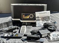 Photo showing the full Sirius XM Onyx satellite radio kit including radio unit, docking cradle, two remote controls, power adapter, antenna, and quick start guide.