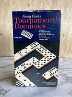 Closed box showing blue packaging with product name 'Family Classics Tournament Dominoes' and images of dominoes arranged.