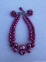 Two-strand pink beaded necklace with silver-tone clasp, strands include round and faceted beads of varying sizes.