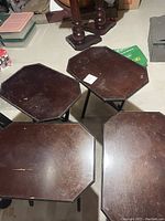Top view of four octagonal dark wooden tables with visible scratches and wear marks.