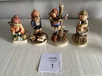 Front view of the four Goebel Hummel figurines arranged in a line showing detailed hand-painted features