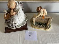 Two collectible sculptures shown side by side, one mounted on a wooden base, the other on a flat base with detailed ground texture.