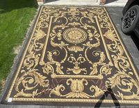 Full view of the vintage brown and gold wool rug laid out outside showing overall pattern and condition.