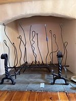 Iron decorative fireplace screen with twisted and swirling rods inside a fireplace opening.