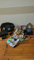 Full view of assorted vintage items on wooden table including bags, trinket boxes, frames, and collectibles