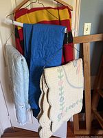 Quilts, comforter, and wool blanket hanging on rack showing colors and patterns