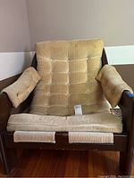 Front view of beige corduroy cushioned wood sling chair showing stains and wear on fabric and some scratches on wood.
