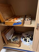 Overall view of shelf with wooden chess board, chess pieces in containers, and a wooden backgammon board with pieces.