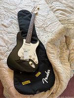Full-body view of black Stratocaster on soft case