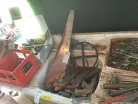 Photo showing pipe wrenches, hand saws, and other tools on a workbench.