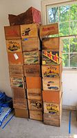 Front view of stacked wood fruit boxes showing several vintage labels with wear and some damage.