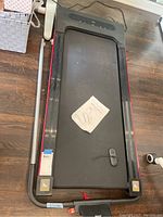Top view of treadmill showing the running belt with owner's manual resting on it and foldable frame structure.