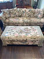 Front view of the rolling ottoman matching floral patterned sofa behind it.