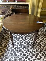 Round walnut wood dining table top showing scratches and natural wood grain with table legs visible.