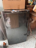 Front view of the small black Frigidaire mini fridge showing the exterior and the Frigidaire logo on the top door edge.