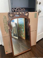 Full front view of the vintage wall mirror showing its overall shape and reflective glass.