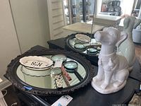 Overview of lot showing ceramic dog, oval mirror, trinket dish, and two magnifying glasses on dark table.