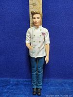 Full view of 2014 Ken Barbie doll in chef outfit, standing in front of a ruler showing height.