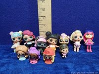 Front view of all 11 LOL OMG dolls figures with a ruler for size reference.
