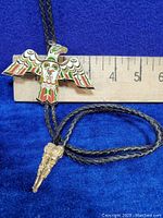 Full view of Thunderbird bolo tie pendant with size reference against ruler showing about 2.5 inches width.