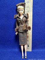 Full view of vintage Barbie doll standing against ruler showing height approximately 11.5 inches. Doll wears tweed wool suit with fur trim at collar and cuffs, black heeled sandals.