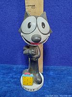 Front view of the Felix the Cat bobble head with measuring ruler showing approximately 7.5 inches in height, showing details of face and pose.