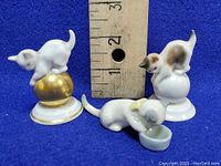Three vintage porcelain cat figurines displayed with ruler for scale, showing measurements around 3 inches tall.