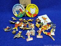 Overview of assortment of Rupert Bear collectible enamel pins and pinbacks in various poses and styles, including some with 'ALD' banners.