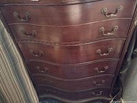 Front view of the solid wood chest of drawers showing 6 drawers with metal handles and carved wood accents.