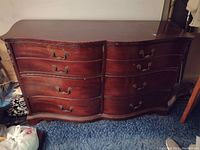Front view of the wood bureau showing the eight drawers with brass handles and the curved wood finish.